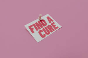 一張粉紅色卡片，上面釘有訊息「Find a Cure」，背景為粉紅色。