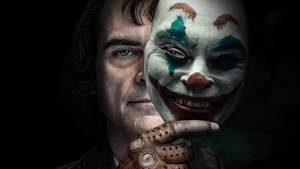 男人在黑暗環境中手持塗色的小丑面具。