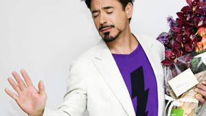 羅拔·唐尼手持一束紫色花朵，同時用手做手勢。