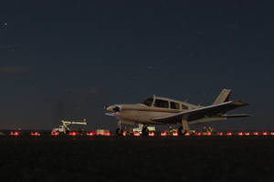 夜間停放的小型飛機，星空和紅色跑道燈。 — 飛機 壁紙