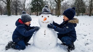 兩個穿著冬季裝備的孩子在雪地公園裡堆雪人。 — 聖誕節 壁紙