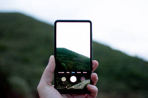 手拿著手機拍攝綠色山丘 — Xiaomi 壁紙
