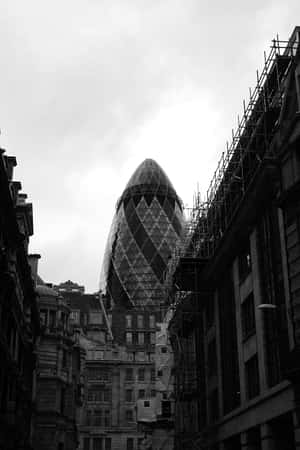 Gherkin摩天大樓被較舊的建築物框住，天空多雲。