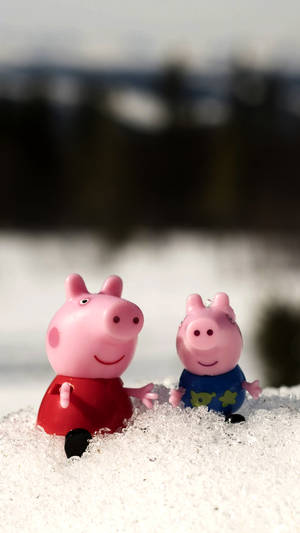 兩個 Peppa Pig 玩具坐喺雪中，背景係森林。