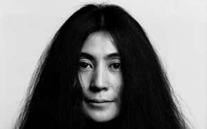 長黑髮女性的黑白特寫肖像，注視著觀看者。