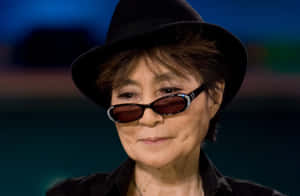 一位戴黑色帽子和水鑽太陽眼鏡的女性直視鏡頭。