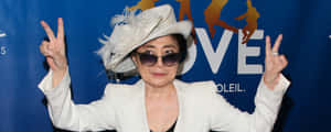 戴白色帽子和太陽眼鏡的女性在活動中比出和平手勢。