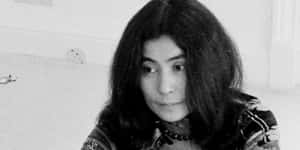 一位長黑髮女性穿著圖案上衣和項鍊，直視鏡頭。