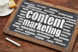 黑板上有 content marketing 術語，周圍有杯子和糕點在木桌上。