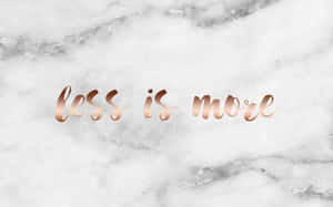 白色大理石背景上的玫瑰金色 Less is more 文字