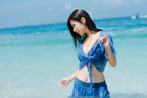 身穿藍色裙子的女性站在海水中，周圍有水花飛濺。