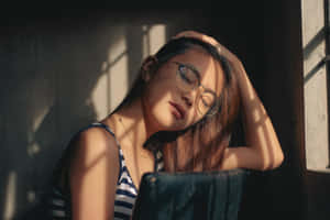 戴眼鏡的年輕女子在窗邊陽光下靜靜休息。