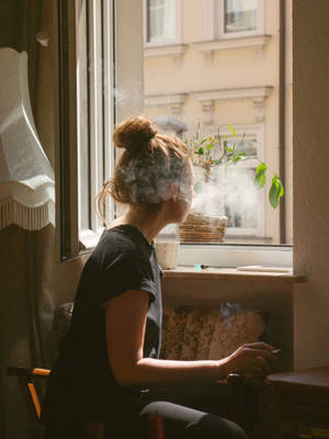 女士在陽光窗邊抽煙，舒適房間