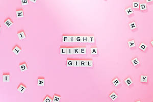 粉紅色背景上，白色字母瓷磚拼出「Fight Like A Girl」，周圍散落著字母。
