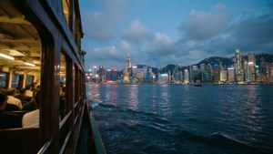 渡輪乘客從移動的船上觀看黃昏時分的香港天際線。