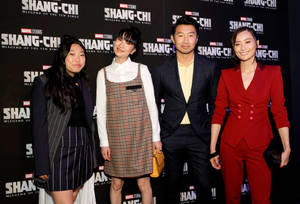 四位微笑的人們在Shang-Chi電影首映活動中穿著正式服裝。