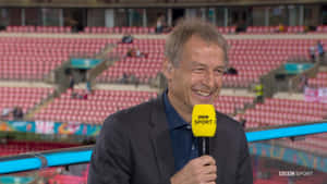 BBC Sport記者喺空嘅體育場微笑住揸住咪高峰。
