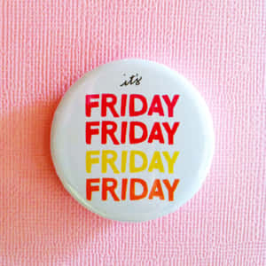 一個白色按鈕，帶有紅色和黃色的「it's FRIDAY」文字，背景為粉紅色紋理。