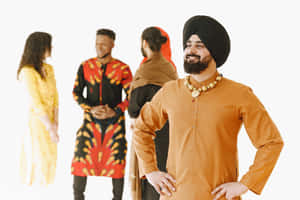 一名身穿橙色庫爾塔和黑色頭巾的男子雙手叉腰微笑，被穿著傳統服飾的人們包圍。