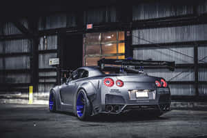 訂製啞光灰色日產GT-R，配備藍色輪圈，停泊在黑暗的倉庫中。