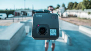 一個GoPro相機指向觀看者，背後有一個人失焦。