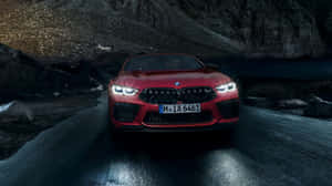 紅色BMW M8 Coupe在夜間穿過湖邊的山區地形。