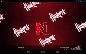 帶有 Huskers 標誌和散落球隊名稱文字的紅色壁紙。