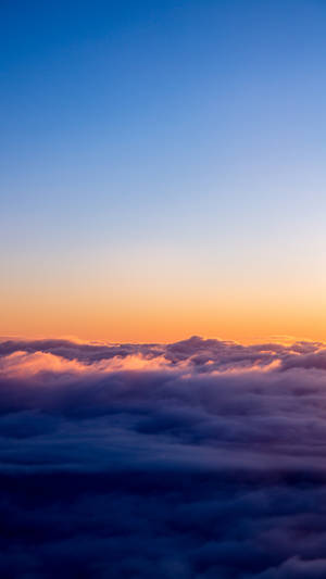 藍色和橙色天空中沐浴在日出色彩中的雲層鳥瞰圖。