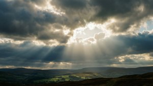 陽光穿透暴風雲，照耀在綠色山谷景觀上。 — 天空 壁紙