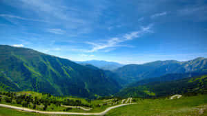 在晴朗的藍天下蜿蜒穿過綠色山谷的道路。