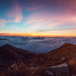 山脊俯瞰雲海，夕陽下天空色彩繽紛。 — 太陽 壁紙