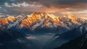 日出照亮了聳立於霧氣山谷之上的雪山。