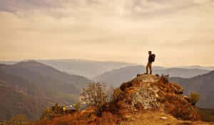 徒步旅行者在山頂俯瞰金色時刻的森林山谷。