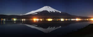 夜晚的富士山，湖中倒影和遠處燈光。 — 美學 壁紙