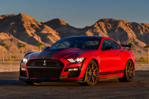 紅色Shelby GT500跑車停在沙漠公路上，遠山夕陽相伴。