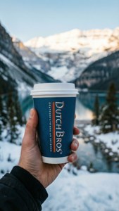 手喺積雪嘅山景中拎住Dutch Bros咖啡杯。