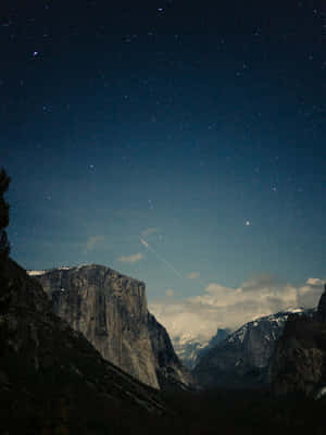 一顆流星劃過積雪覆蓋的山峰之上的星空夜空。 — 肖像 壁紙