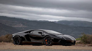 黑色林寶堅尼 Aventador 在泥路上，陰天下以山巒為背景