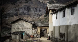 一個安靜的山村，有石屋和一個人坐在門口附近。