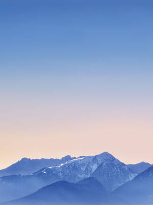 在柔和粉紅和藍色黎明天空下的雪山