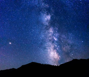 銀河系在黑暗的山峰之上，橫跨繁星點點的夜空。 — 星星 壁紙