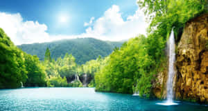 一個寧靜的湖泊，瀑布在陽光明媚的天空下流經森林覆蓋的山谷。