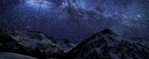 白雪覆蓋的山脈在明亮的星空下，銀河清晰可見。