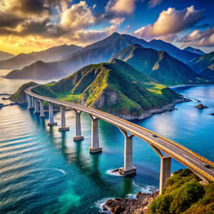 在金色日落天空下，一座長長的混凝土橋橫跨在綠色山脈之間的碧綠海水上。