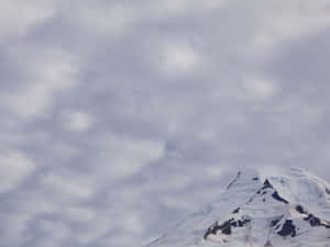 陰天時白雪覆蓋的山峰從灰色雲層中升起。