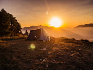 日出時在山脊上搭建的帳篷，背景有霧氣繚繞的山峰。