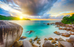 熱帶海灘上的夕陽，碧綠海水與大岩石