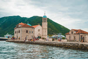 海濱碼頭上的藍色圓頂石砌教堂，有遊客和船隻 — 島嶼 壁紙