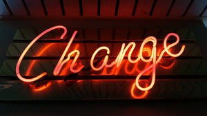 一個發光的紅色霓虹燈牌，上面寫著「Change」，安裝在深色木牆上。