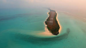 日出時分，在熱帶島嶼上建造的跑道，周圍環繞著碧綠海水。